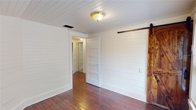 empty room featuring a barn door and dark wood-type flooring