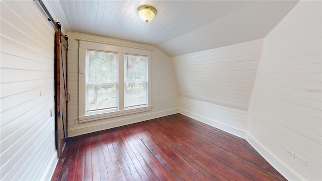 additional living space featuring dark hardwood / wood-style floors, wooden walls, and vaulted ceiling