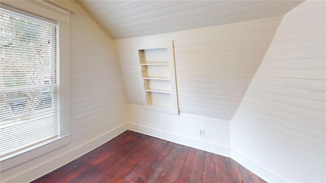 spare room featuring hardwood / wood-style floors, wooden walls, built in shelves, and lofted ceiling