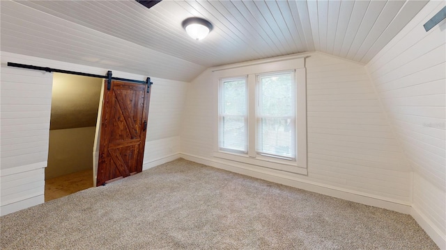 unfurnished bedroom with a barn door, carpet floors, wood ceiling, and lofted ceiling