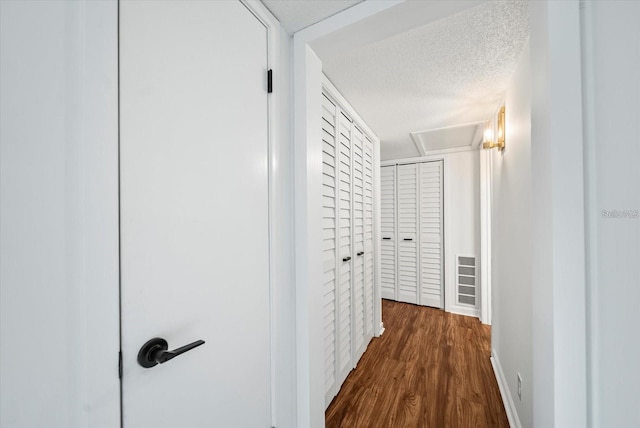 corridor with a textured ceiling and dark hardwood / wood-style floors