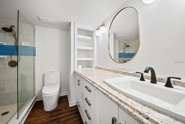 bathroom featuring tiled shower, toilet, vanity, and wood-type flooring