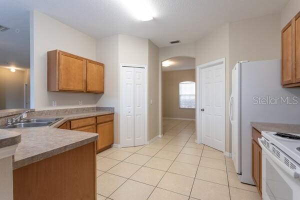 kitchen with white electric stove, sink, and light tile patterned floors