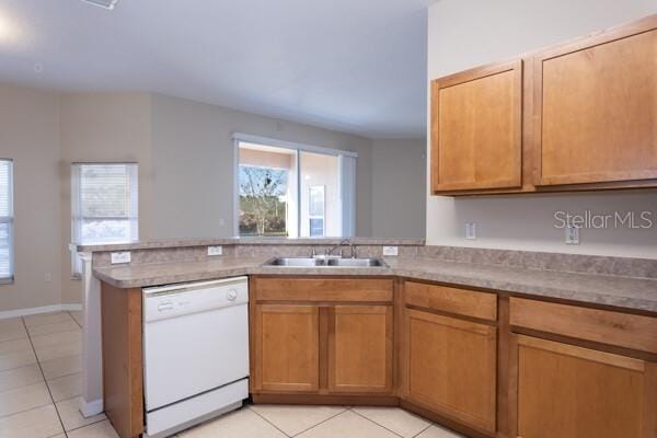 kitchen with light tile patterned flooring, white dishwasher, kitchen peninsula, and sink