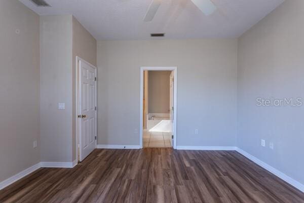 unfurnished bedroom featuring ensuite bathroom, dark hardwood / wood-style floors, and ceiling fan