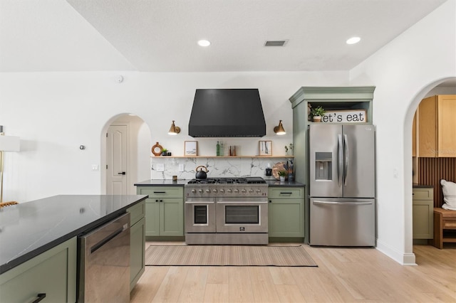 kitchen featuring green cabinetry, stainless steel appliances, extractor fan, and light hardwood / wood-style flooring