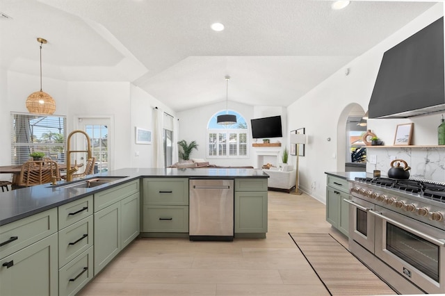 kitchen with double oven range, lofted ceiling, sink, green cabinetry, and decorative light fixtures