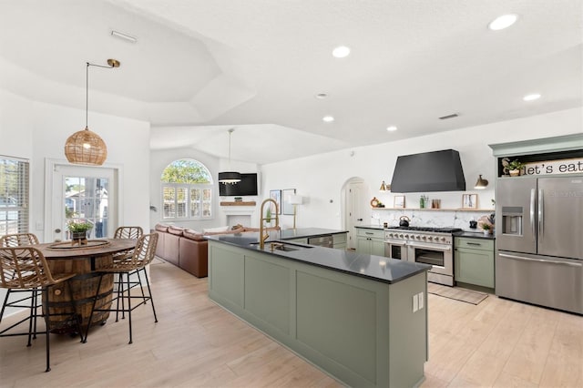 kitchen featuring appliances with stainless steel finishes, sink, pendant lighting, green cabinetry, and range hood