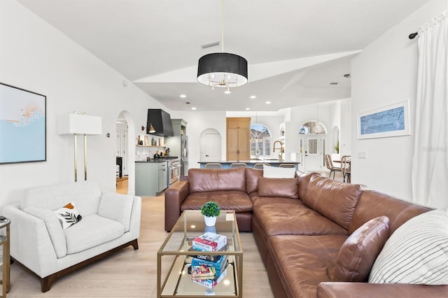 living room featuring sink, vaulted ceiling, and light wood-type flooring