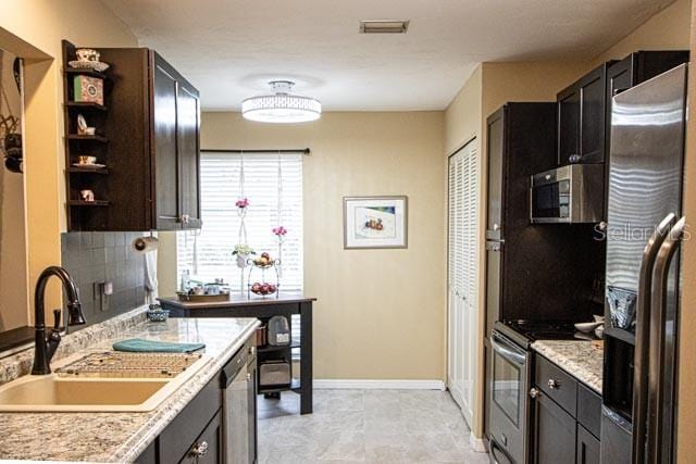 kitchen featuring appliances with stainless steel finishes, decorative backsplash, dark brown cabinets, and sink