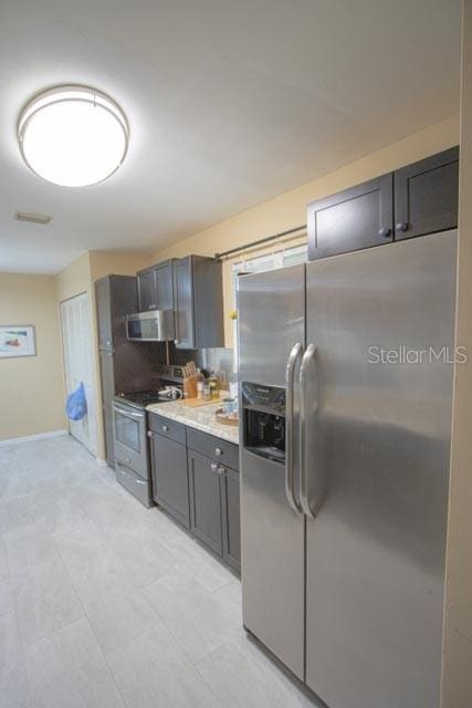 kitchen featuring light stone countertops, backsplash, and appliances with stainless steel finishes