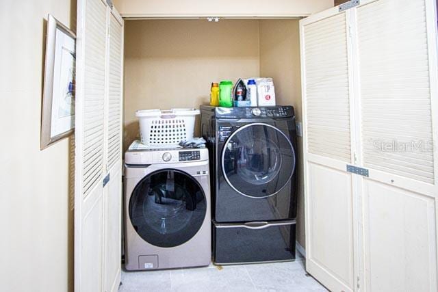 clothes washing area with light tile patterned floors and separate washer and dryer