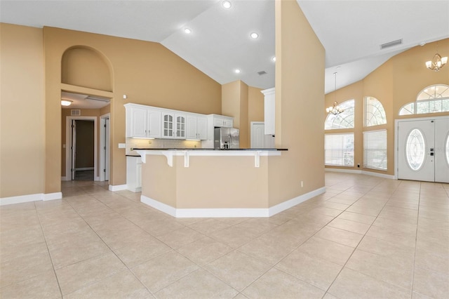 kitchen with stainless steel fridge with ice dispenser, an inviting chandelier, white cabinets, a peninsula, and a kitchen bar