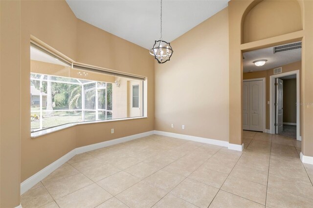 empty room featuring baseboards, visible vents, a chandelier, and light tile patterned flooring