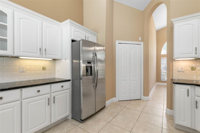 kitchen with arched walkways, stainless steel fridge, glass insert cabinets, and white cabinets