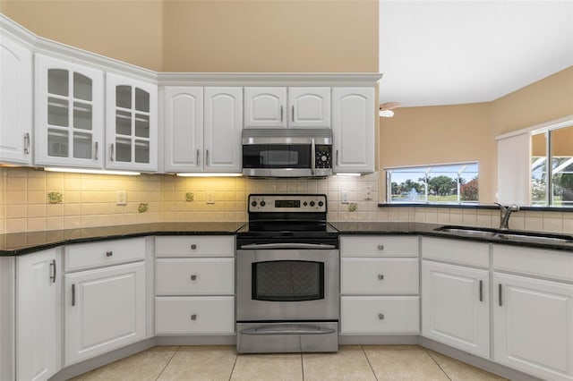 kitchen featuring decorative backsplash, appliances with stainless steel finishes, glass insert cabinets, white cabinetry, and a sink