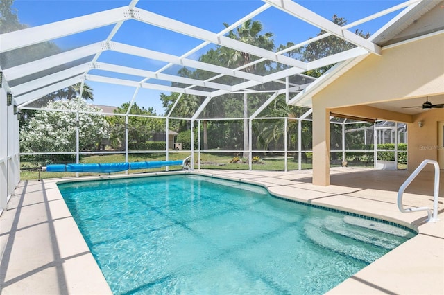 view of pool featuring glass enclosure, a patio area, a ceiling fan, and a covered pool