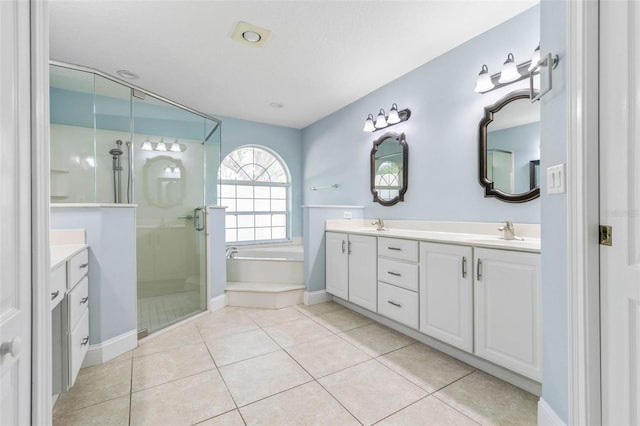 bathroom featuring double vanity, a stall shower, tile patterned floors, a garden tub, and a sink