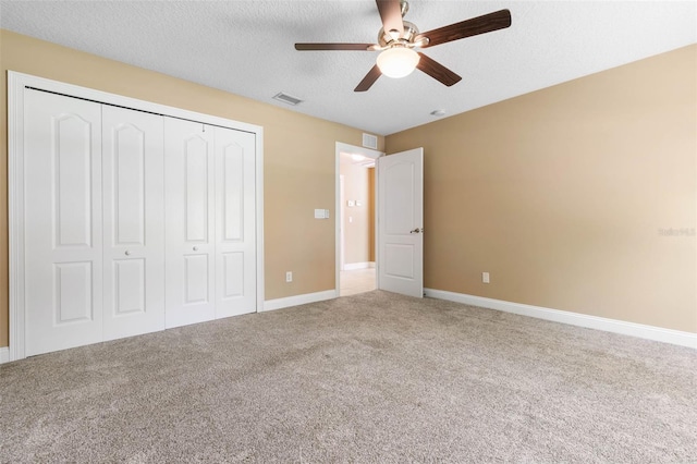 unfurnished bedroom featuring carpet floors, a closet, visible vents, and a textured ceiling