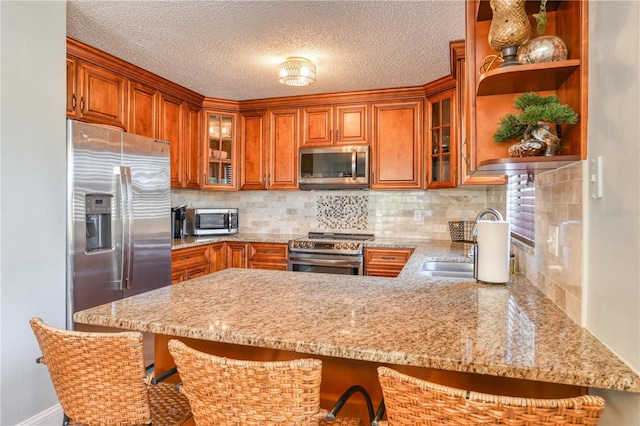 kitchen featuring sink, tasteful backsplash, kitchen peninsula, a breakfast bar area, and appliances with stainless steel finishes