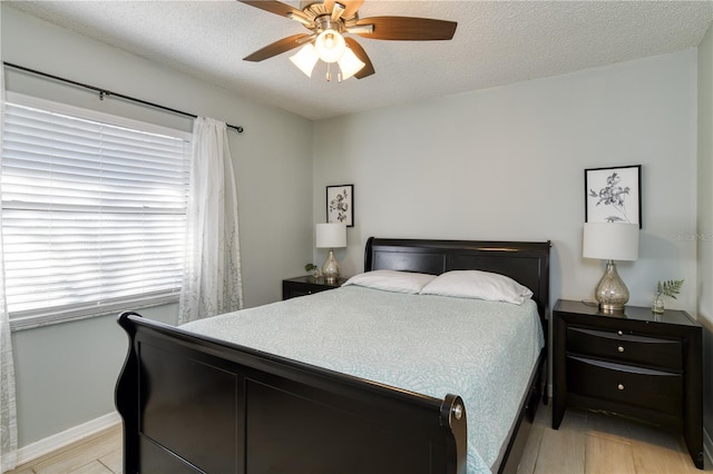 bedroom with a textured ceiling, light hardwood / wood-style floors, and ceiling fan