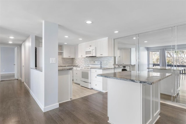 kitchen featuring hanging light fixtures, white appliances, white cabinets, and a kitchen island