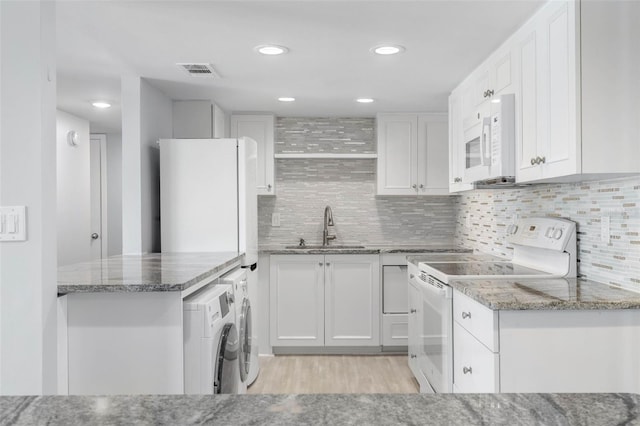 kitchen with sink, white cabinetry, stone counters, white appliances, and washer / clothes dryer