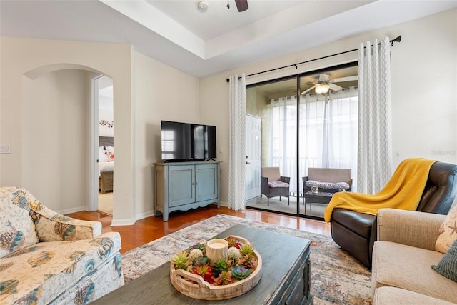 living room featuring hardwood / wood-style floors, a tray ceiling, and ceiling fan