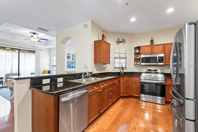 kitchen featuring sink, ceiling fan, appliances with stainless steel finishes, light hardwood / wood-style floors, and kitchen peninsula