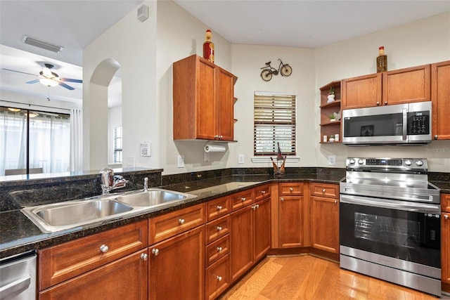 kitchen featuring sink, ceiling fan, dark stone countertops, light hardwood / wood-style floors, and stainless steel appliances