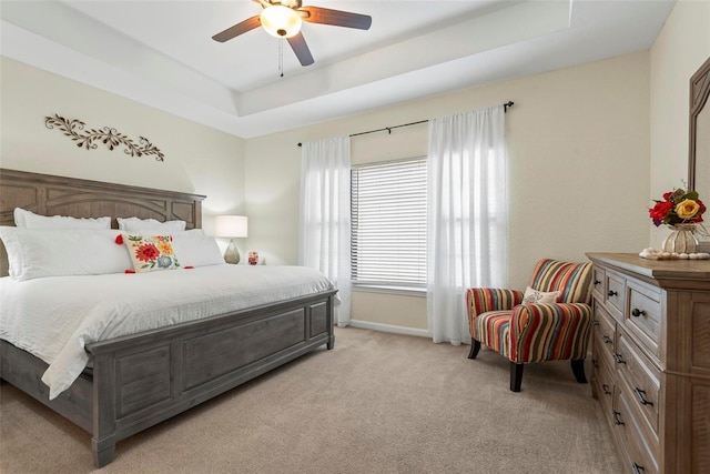 bedroom featuring light carpet, a raised ceiling, and ceiling fan