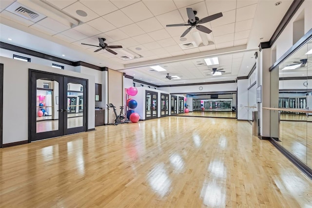 interior space featuring a drop ceiling, light wood-type flooring, and french doors