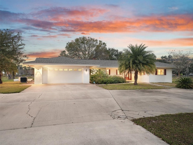 view of front of house with a garage, a lawn, and central air condition unit