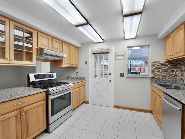 kitchen with light stone countertops, decorative backsplash, stainless steel appliances, sink, and light tile patterned floors