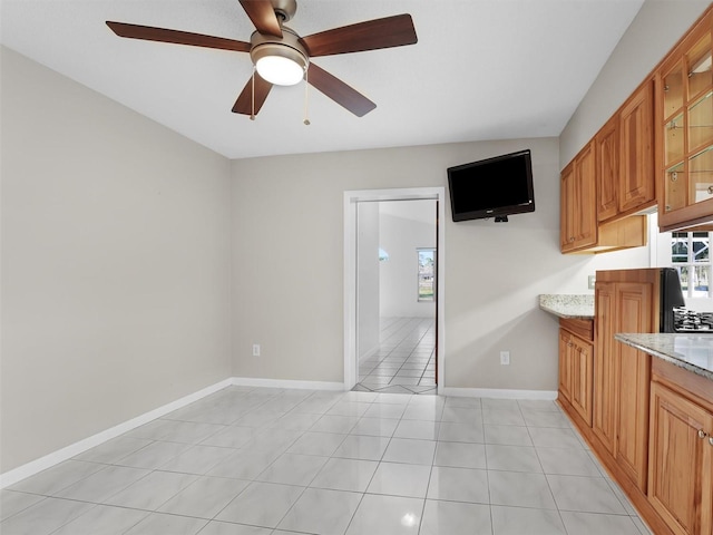 kitchen featuring ceiling fan, a healthy amount of sunlight, light stone counters, and light tile patterned floors