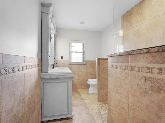 bathroom featuring tile patterned floors, vanity, toilet, and tile walls