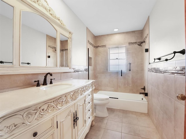 full bathroom with tile patterned floors, vanity, tile walls, toilet, and tiled shower / bath