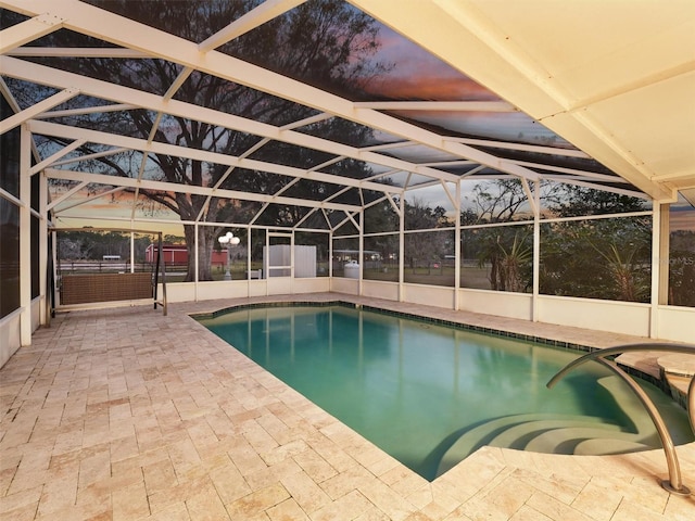 pool at dusk featuring a patio area and a lanai