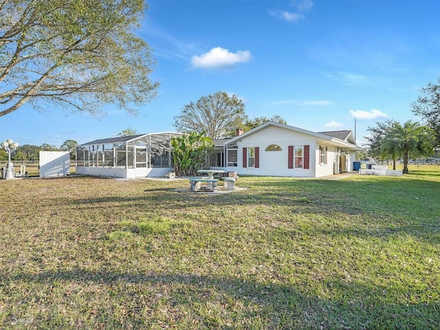 back of property featuring a lawn and glass enclosure