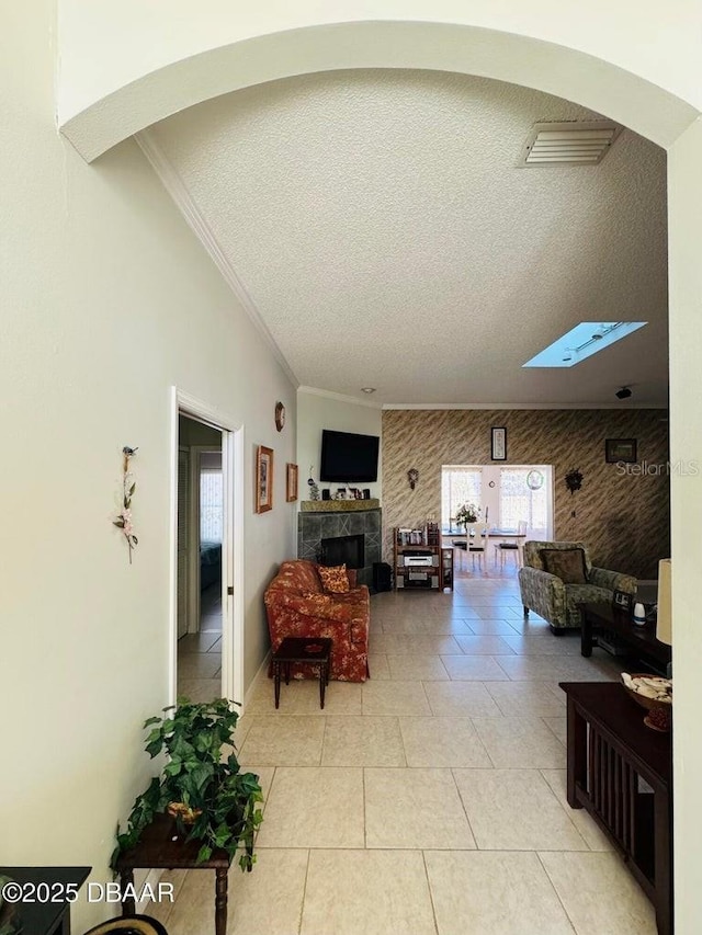 tiled living room featuring a textured ceiling, a skylight, and ornamental molding