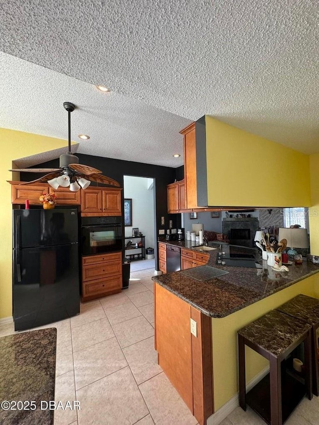 kitchen featuring black appliances, ceiling fan, a textured ceiling, light tile patterned flooring, and kitchen peninsula