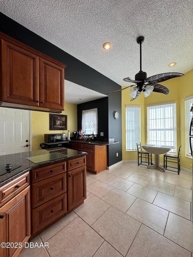 kitchen with ceiling fan, light tile patterned floors, and a textured ceiling