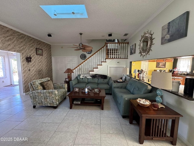 living room featuring a skylight, ceiling fan, ornamental molding, a textured ceiling, and light tile patterned flooring