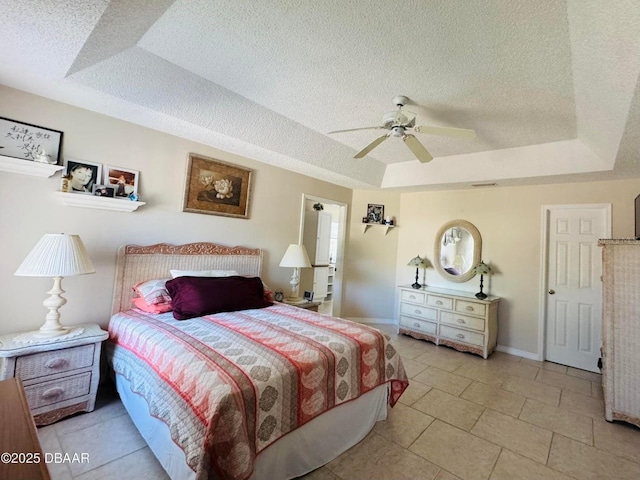 tiled bedroom featuring a textured ceiling, a raised ceiling, and ceiling fan