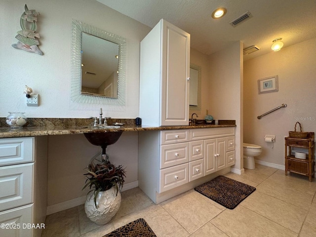 bathroom with tile patterned flooring, vanity, a textured ceiling, and toilet