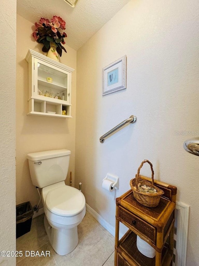 bathroom with tile patterned flooring, toilet, and a textured ceiling