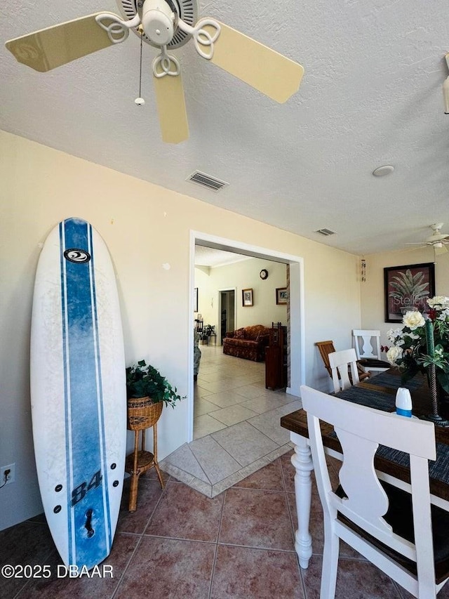 foyer entrance with a textured ceiling, tile patterned floors, and ceiling fan