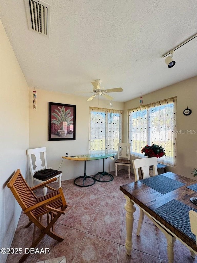 dining space featuring ceiling fan, light tile patterned flooring, a textured ceiling, and track lighting