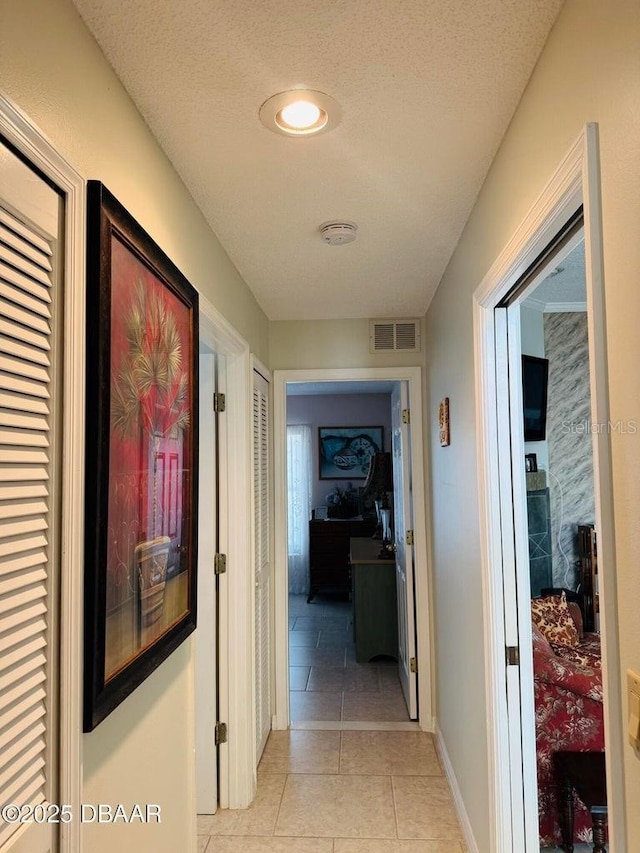 hallway featuring light tile patterned flooring and a textured ceiling