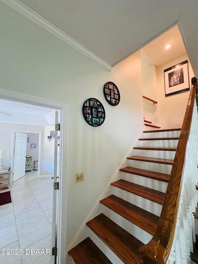 stairway featuring tile patterned flooring, ornamental molding, and a textured ceiling